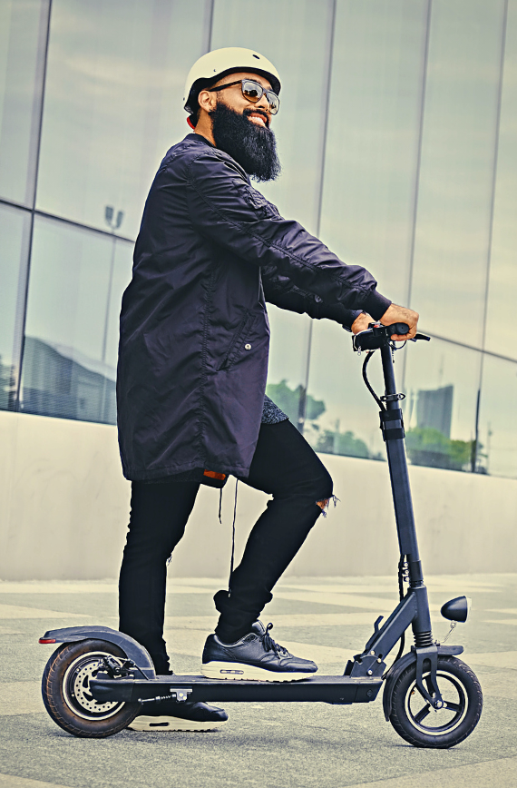 Bearded man wearing a helmet riding a Bullet Stealth electric scooter