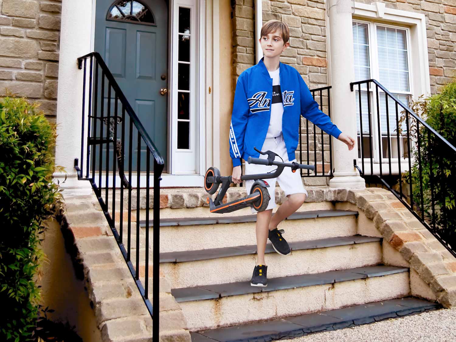 boy walking down the stairs carrying a Ninebot scooter