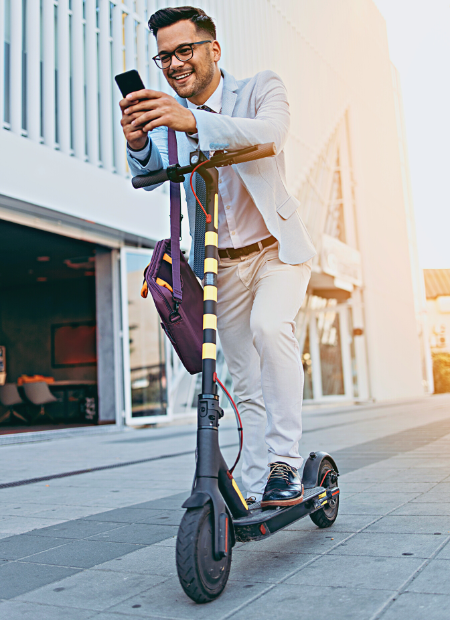 Man using a smartphone while standing on a Ninebot scooter on a sidewalk