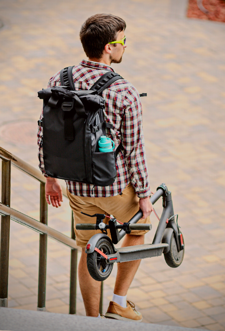 Man carrying a Ninebot scooter while walking down the stairs