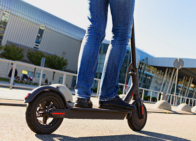 Cropped photo of a man riding a Ninebot e-scooter