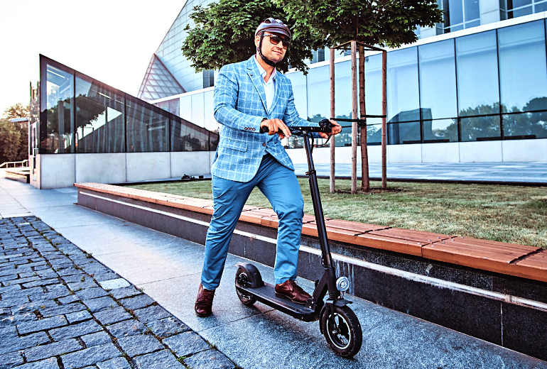 Businessman wearing a helmet standing on a Razor Electric scooter