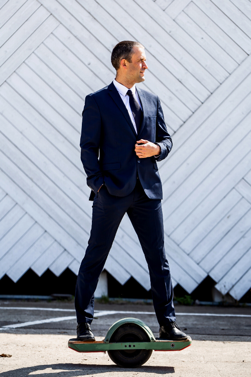 Businessman wearing a suit riding a Onewheel Electric Skateboard to his office