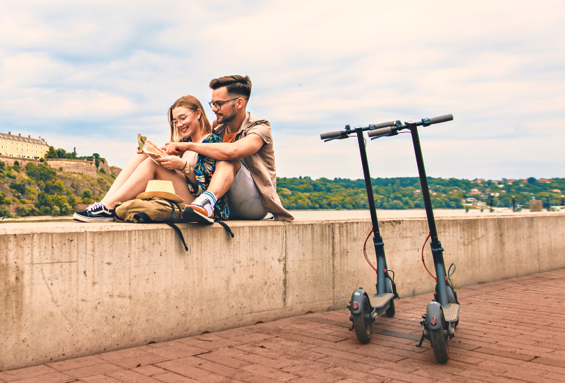 Couple sitting while looking on a map, with their Razor Electric scooters parked
