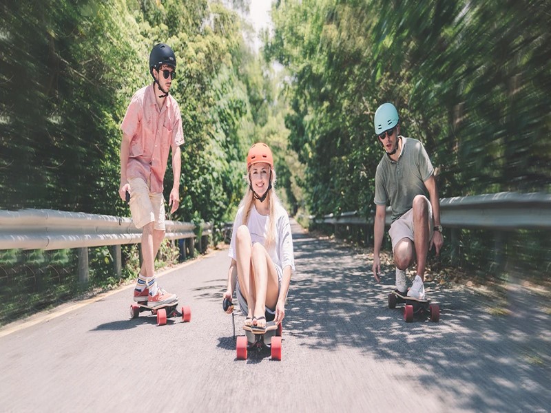 Three friends riding an electric skateboard down the road