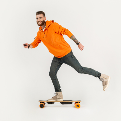 Man in orange hoodie & black jeans riding electric skateboard - My Electric Scooter