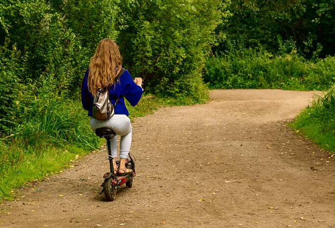 Woman riding an electric scooter with seat on a dirt road