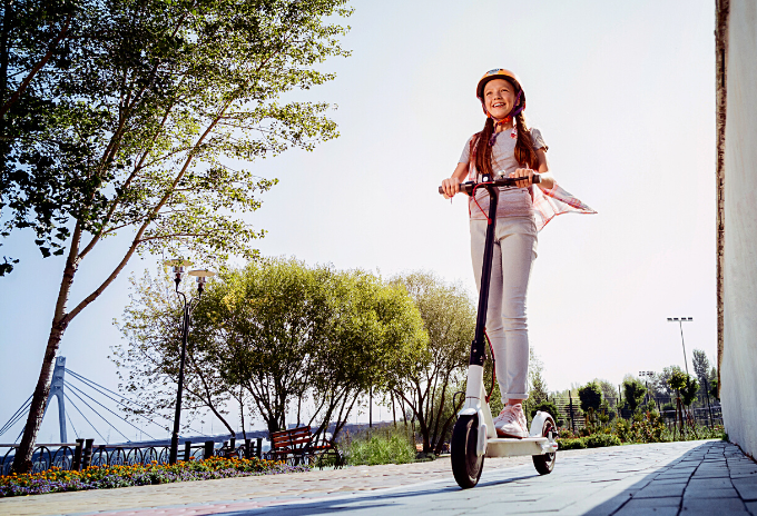 Happy young girl riding an electric scooter