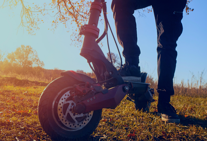 cropped image of a person riding an electric off road scooter during sunrise