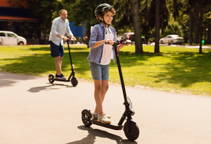 Kid riding an electric scooter accompanied by his parent