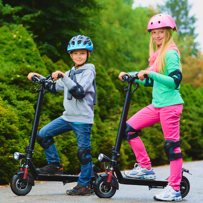 Kids wearing safety gears while riding electric scooters in the park