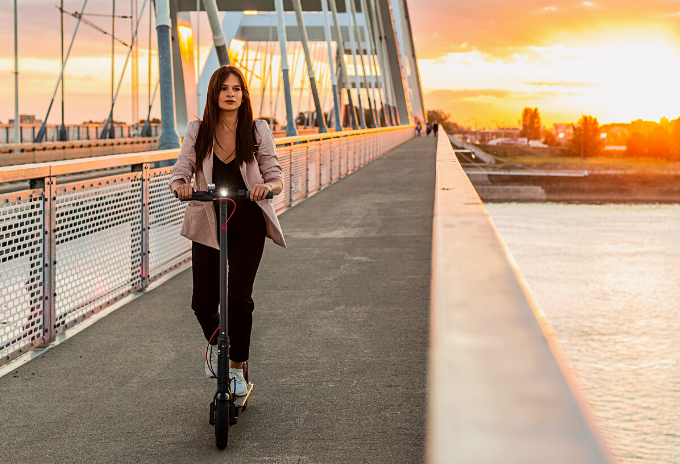 Woman riding an electric scooter on a bridge during sunset