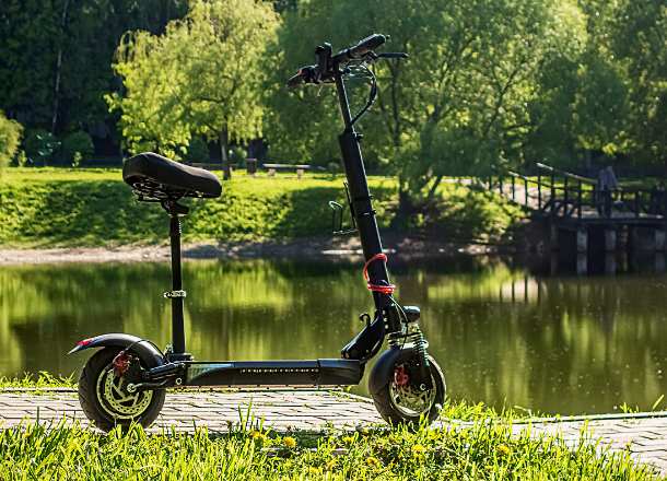 Off road electric scooter with seat parked near a lake