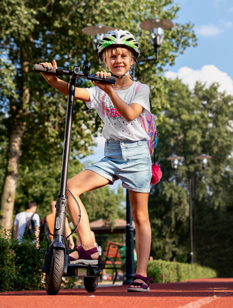 Young girl poses while riding an electric scooter