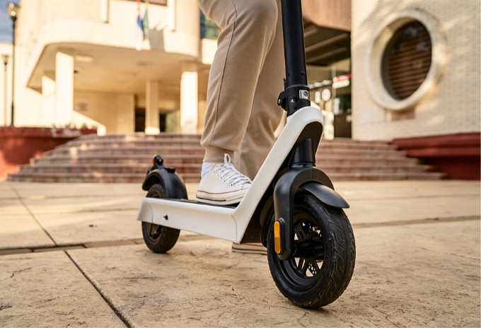 Cropped image of a person riding a black and white electric scooter