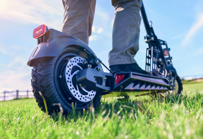Cropped image of a person riding an all terrain electric scooter on a grassland