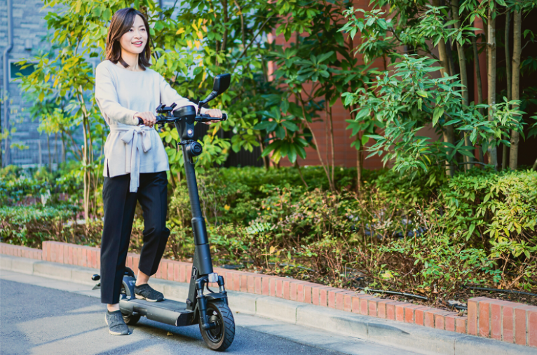 Young woman riding an electric scooter on a garden road