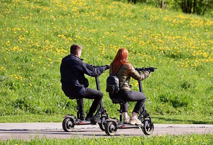 Couple riding seated electric scooter downhill