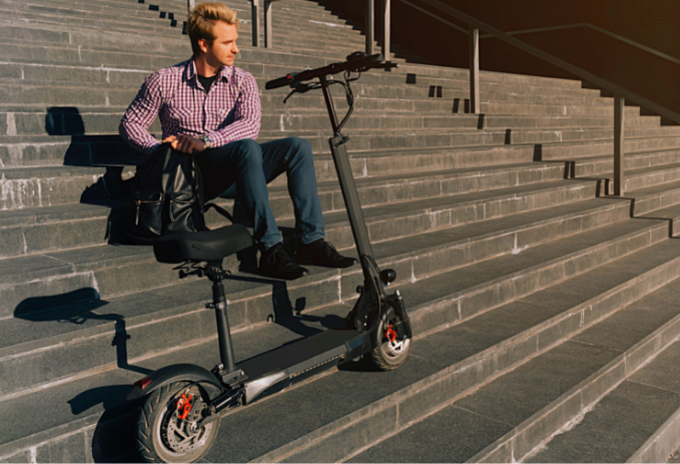 Man sitting in the stairs with a seated electric scooter in front