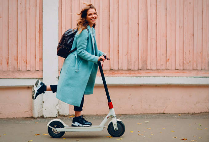 A woman happily rides an electric scooter