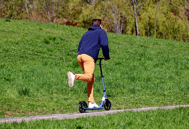 Man riding an electric scooter on a hill one sunny day
